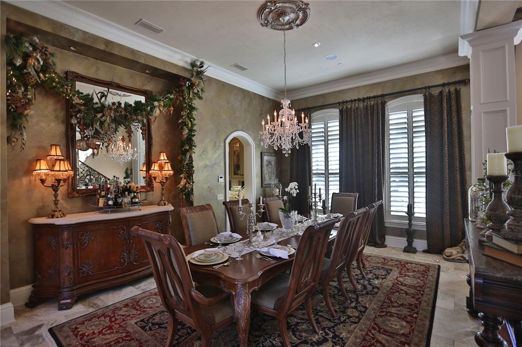 A formal dining room features a long wooden table, crystal chandelier, and ornate wall decor — 15305 NW HWY 320, MICANOPY, FL