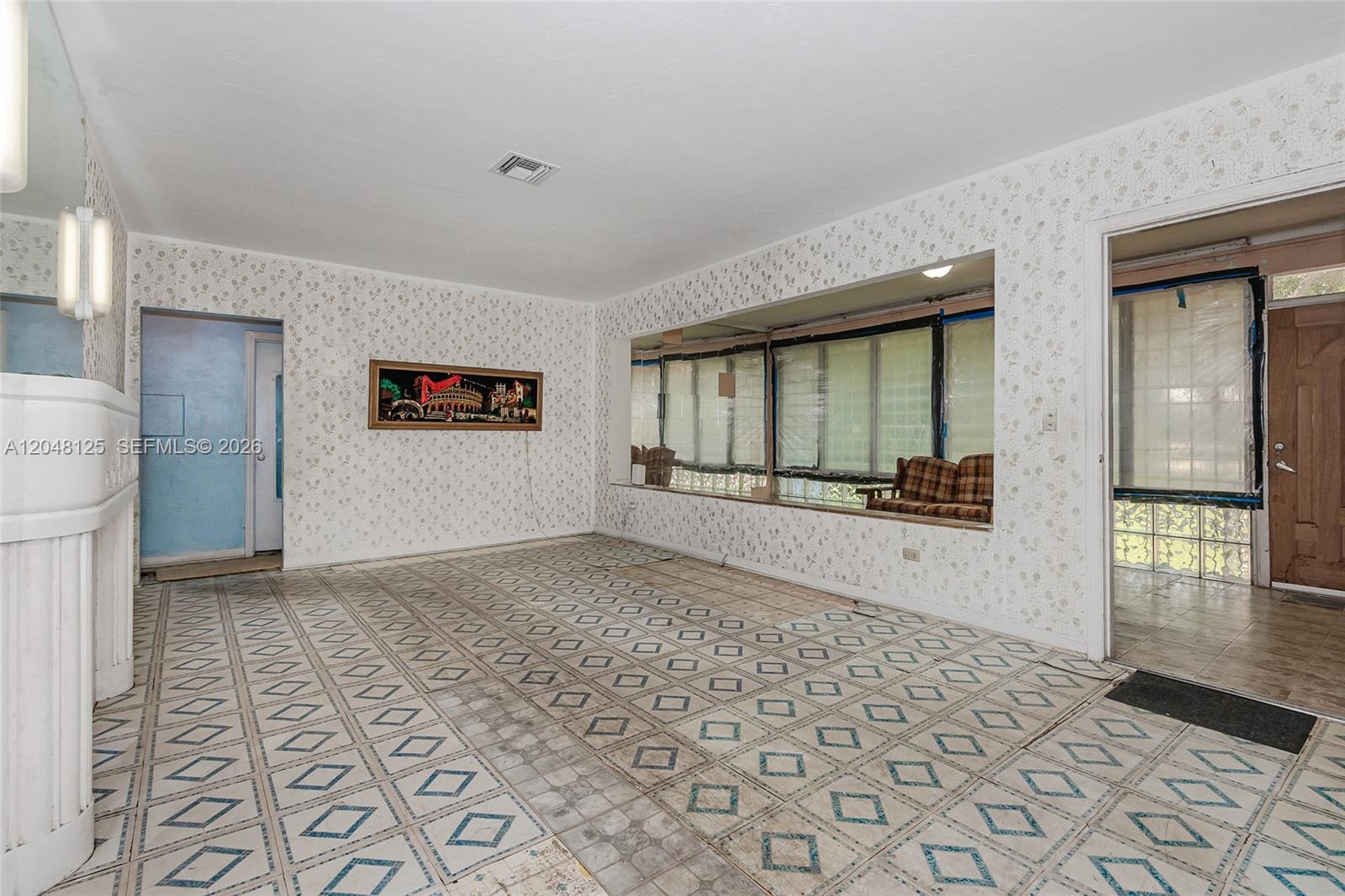 A living room features patterned wallpaper, tiled flooring, a large window, and a fireplace — 245 NE 48th St, Miami FL 33137, MIAMI, FL