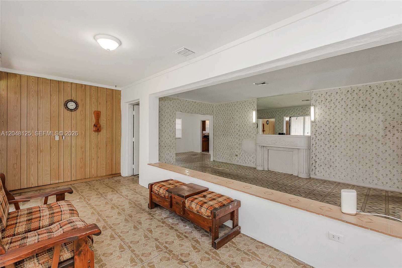 A living area features wood-paneled walls, tile flooring, and a large opening to another room — 245 NE 48th St, Miami FL 33137, MIAMI, FL