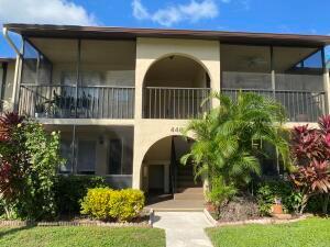 A two-story apartment building features screened balconies, arched entryways, and lush landscaping — 446 Pine Glen Lane # 1, FL 33463, FL