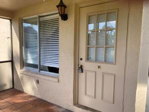 A beige exterior wall features a window with blinds and a door with a window — 446 Pine Glen Lane # 1, FL 33463, FL