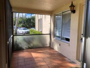 A covered patio with tiled flooring, a screened enclosure, and a window with white blinds — 446 Pine Glen Lane # 1, FL 33463, FL