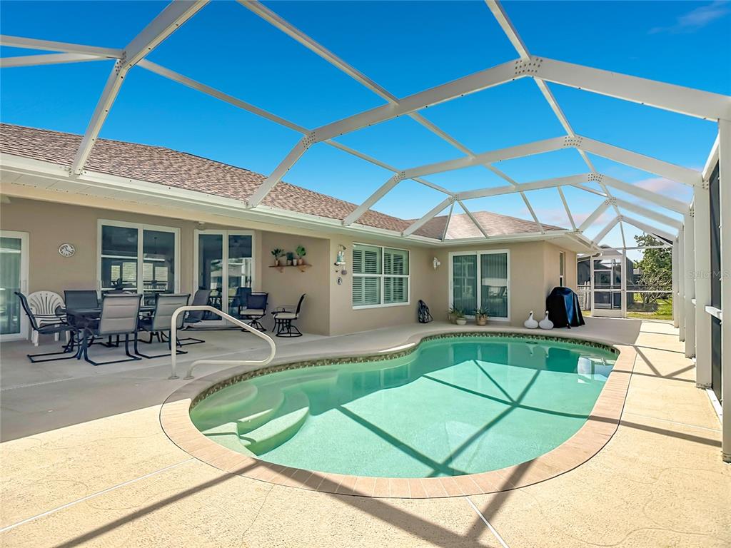 A screened-in patio features a swimming pool with steps and outdoor dining furniture — 70 CLUBHOUSE ROAD, ROTONDA WEST, FL