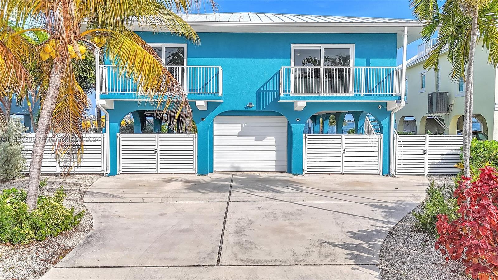 A bright blue two-story house with a central garage and white fenced-in ground level areas — 441 La Fitte Rd # 0, Torch Key FL 33042, TORCH KEY, FL