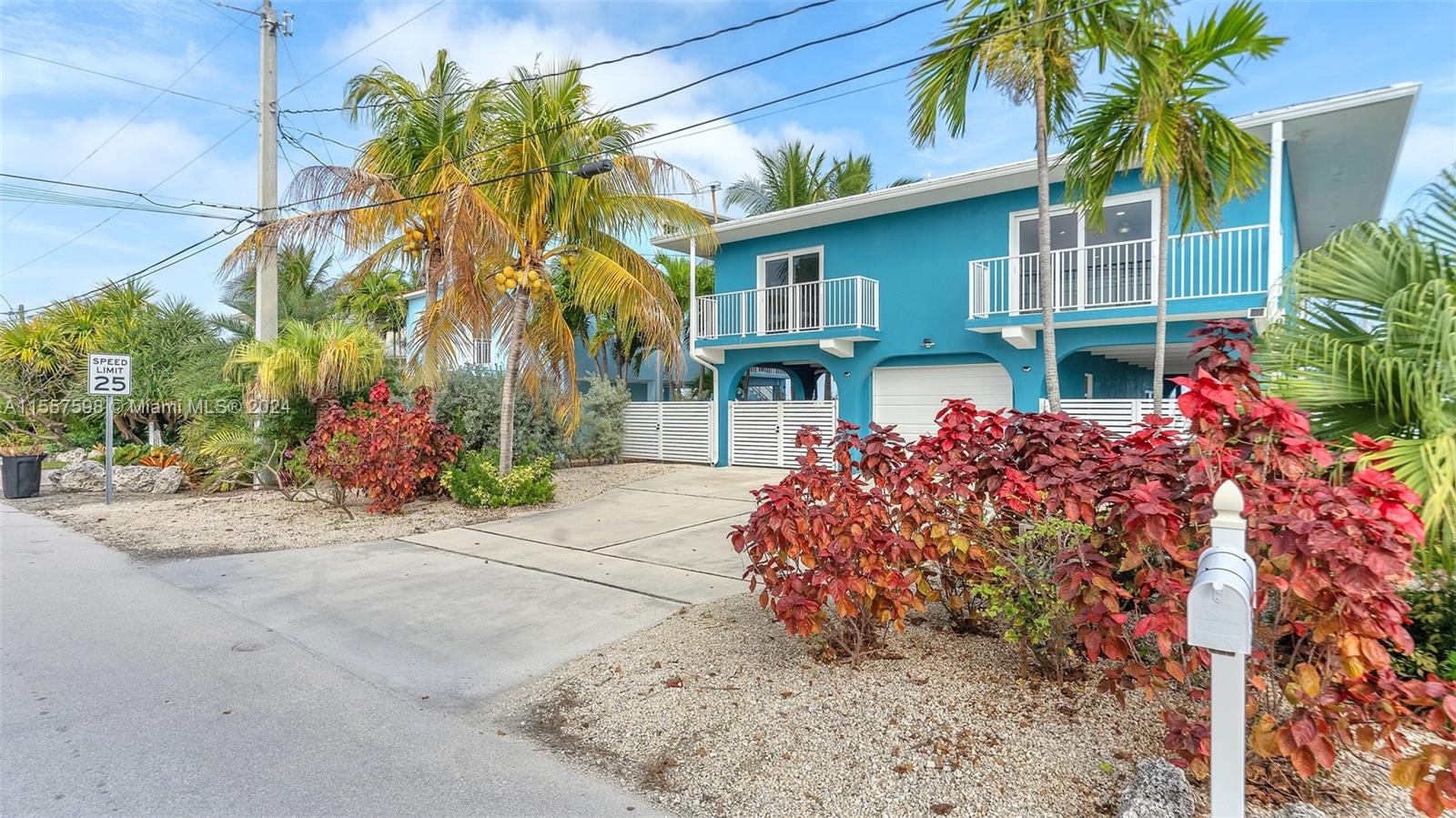 A two-story blue house with a concrete driveway and tropical landscaping sits under a sky — 441 La Fitte Rd # 0, Torch Key FL 33042, TORCH KEY, FL