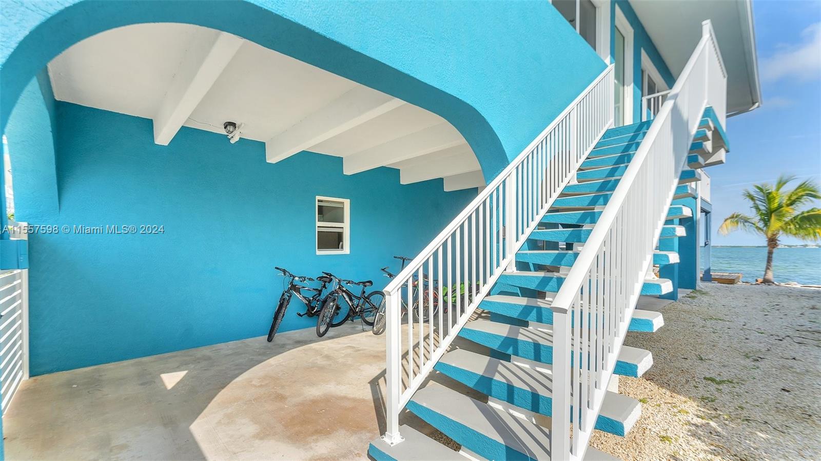 An outdoor staircase leads to an elevated entrance beside a bright blue house — 441 La Fitte Rd # 0, Torch Key FL 33042, TORCH KEY, FL