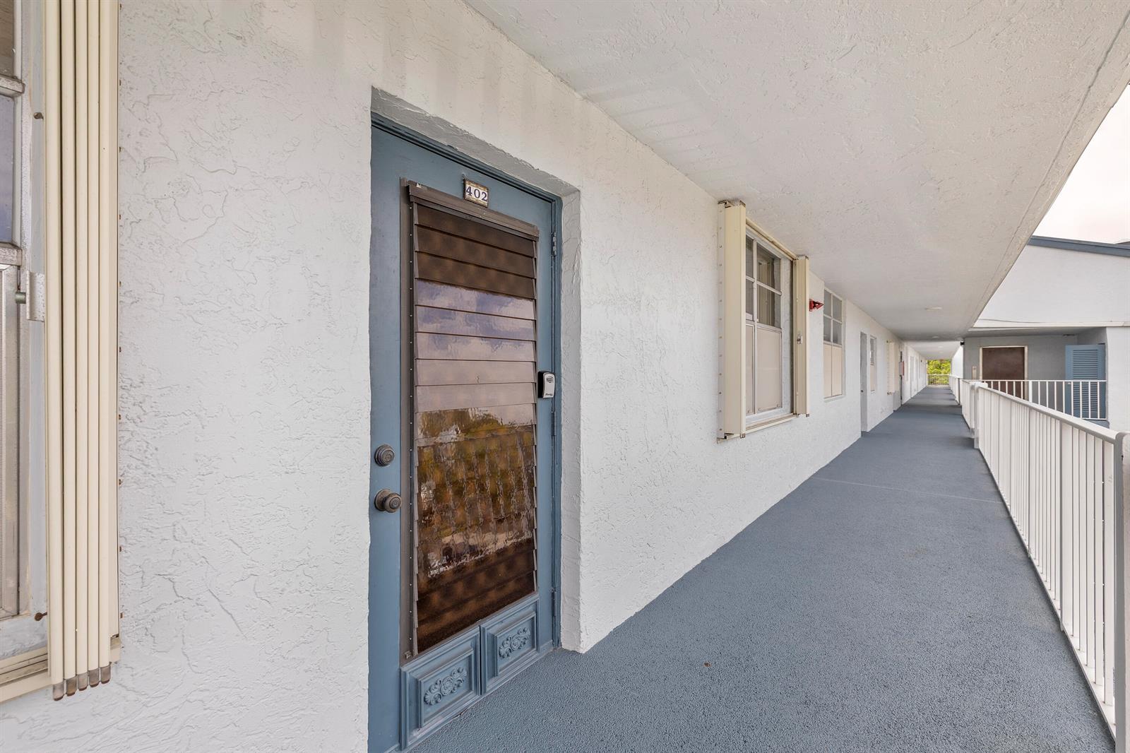 A blue door with a storm screen leads to an outdoor walkway at a building — 1480 NW 80th Avenue # 402, Margate FL 33063, MARGATE, FL