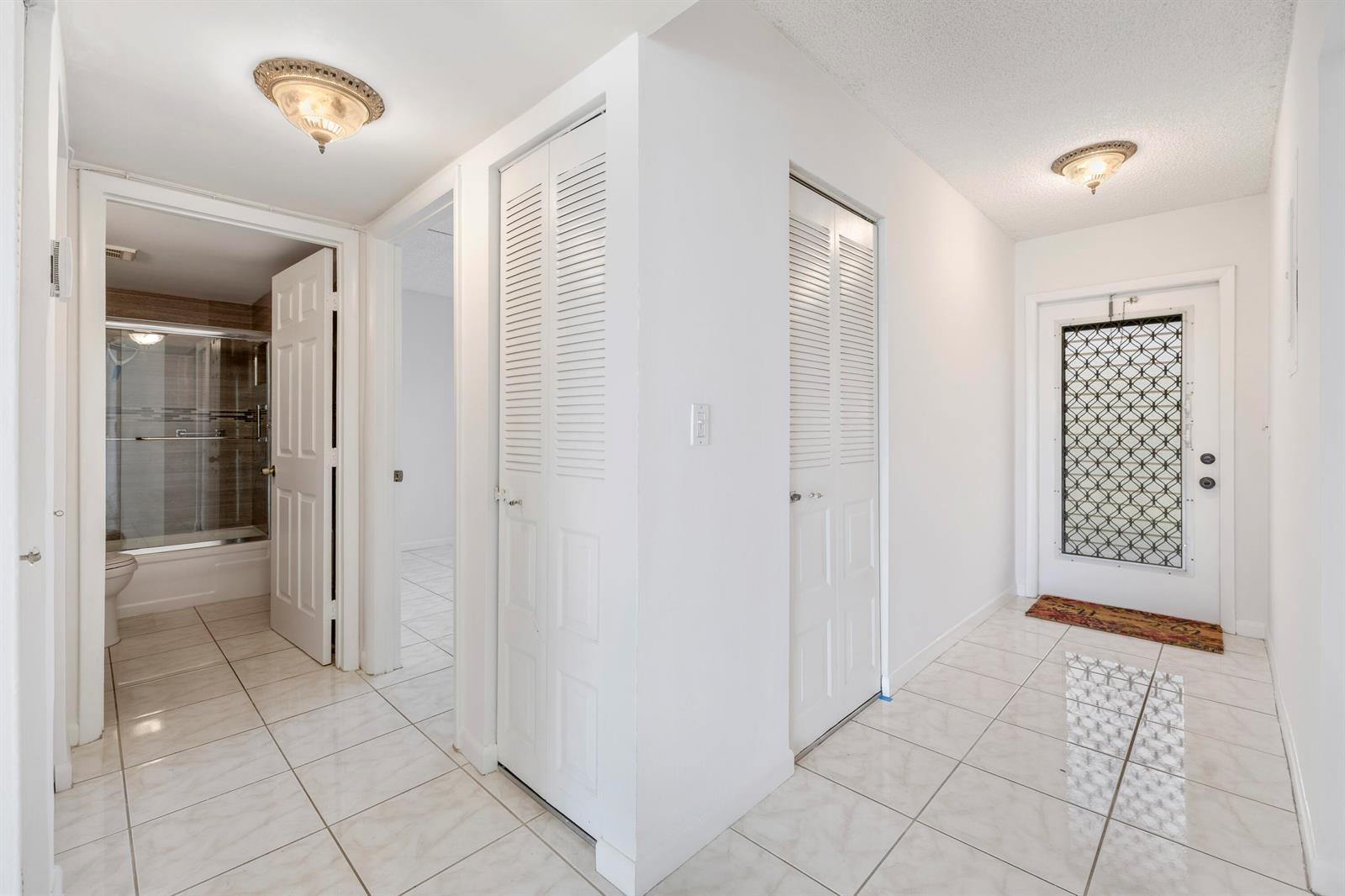 A tiled hallway features two louvered closet doors, a bathroom entrance, and a front door — 1480 NW 80th Avenue # 402, Margate FL 33063, MARGATE, FL
