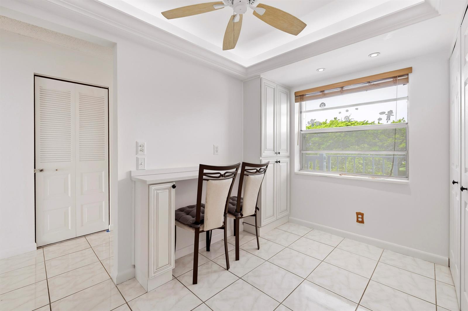 A bright room features white tile floors, a built-in desk, and a window with blinds — 1480 NW 80th Avenue # 402, Margate FL 33063, MARGATE, FL