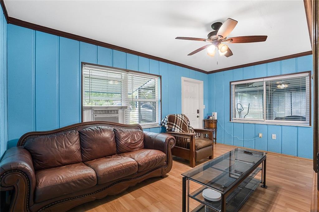 A living room features bright blue paneled walls, a brown leather sofa, and wood flooring — VERO BEACH, FL