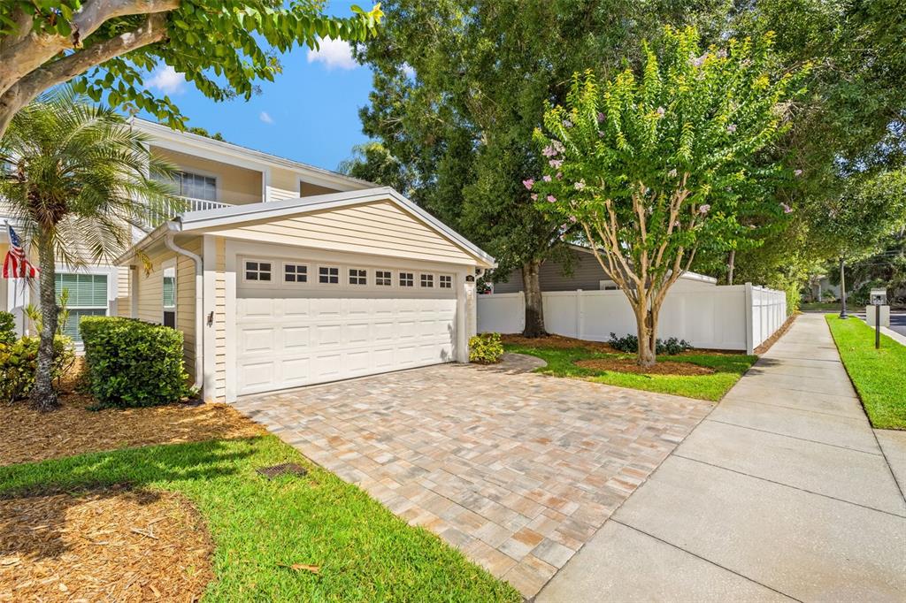 A beige house with a white garage door and a paved driveway next to a sidewalk — 902 WOODBRIDGE COURT, SAFETY HARBOR, FL