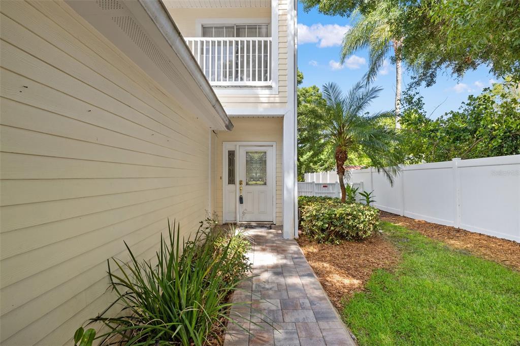 A paved walkway leads to the front entrance of a two-story house with light-colored siding — 902 WOODBRIDGE COURT, SAFETY HARBOR, FL