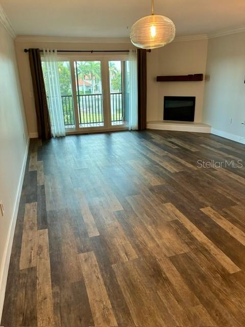 An empty living room features wood-look flooring, a corner fireplace, and sliding glass balcony doors — 2400 FEATHER SOUND DRIVE UNIT 1031, CLEARWATER, FL