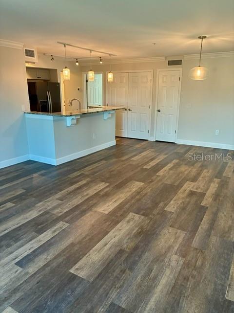 An open-concept kitchen with a breakfast bar and wood-look flooring leads to a hallway — 2400 FEATHER SOUND DRIVE UNIT 1031, CLEARWATER, FL