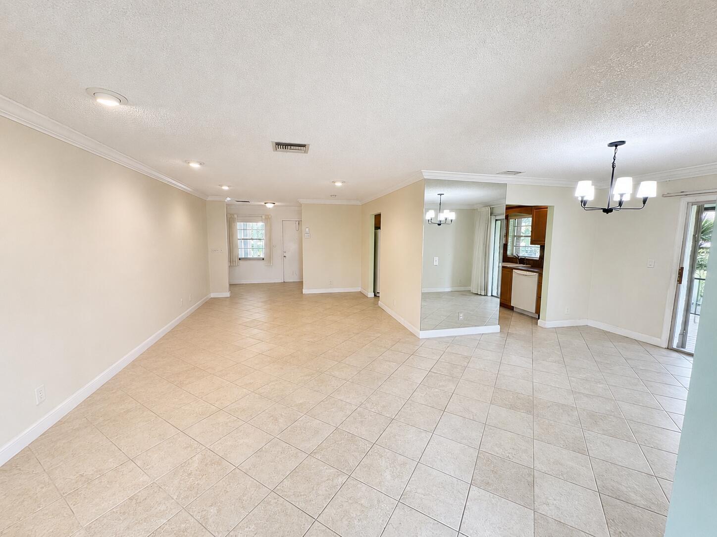 An open-concept living and dining area features beige tile flooring, recessed lighting, and mirrored walls — 6401 Lasalle Drive, Delray Beach FL 33484, DELRAY BEACH, FL