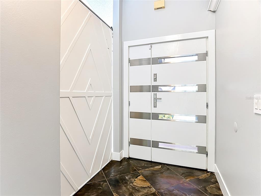 An entryway features a modern white double door with glass inserts and patterned wall paneling — 3247 TIMUCUA CIRCLE, ORLANDO, FL