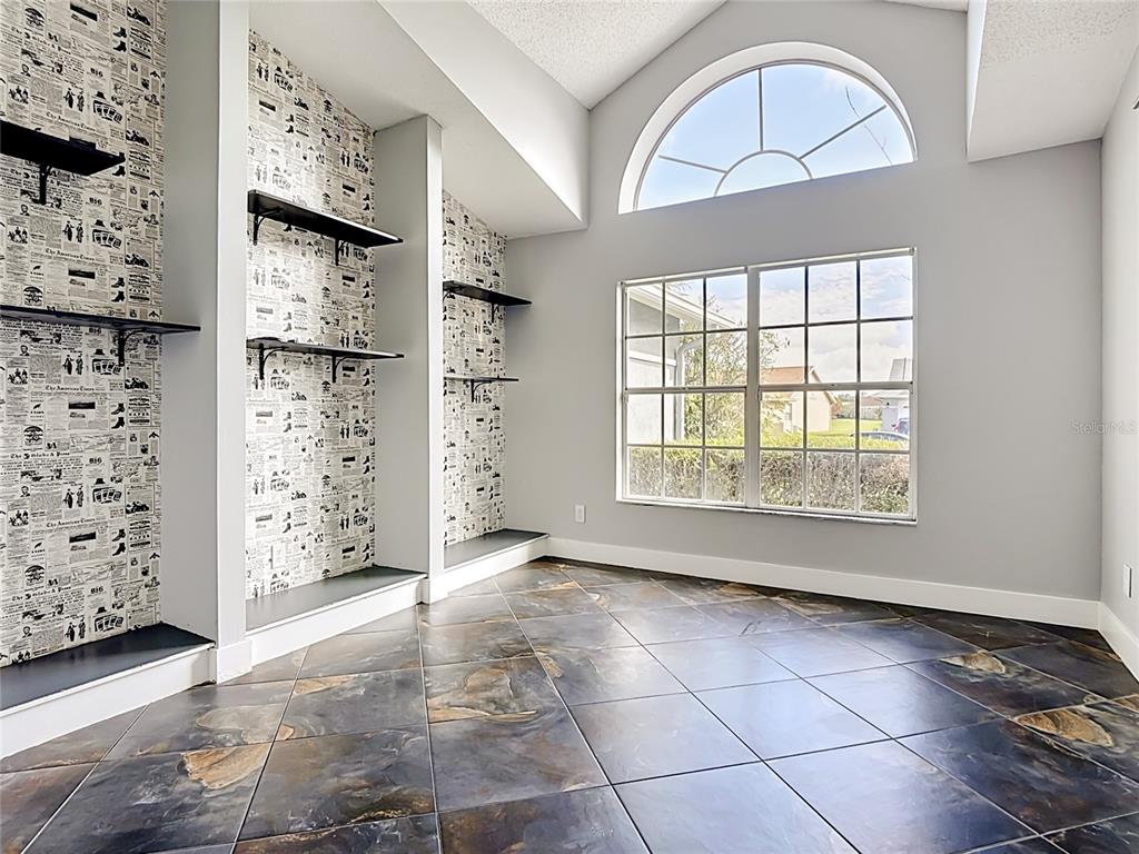 A room features newspaper-patterned wallpaper, built-in shelving, tiled floors, and a large arched window — 3247 TIMUCUA CIRCLE, ORLANDO, FL