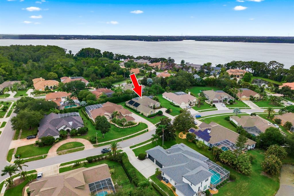 An aerial view shows a suburban neighborhood with a house marked by a red arrow — 5442 MILLBROOK WAY, PALM HARBOR, FL