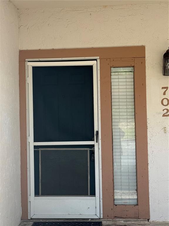 A dark blue front door with a white screen door and a side window panel — 702 COUNTRY LANE NE UNIT 702, WINTER HAVEN, FL