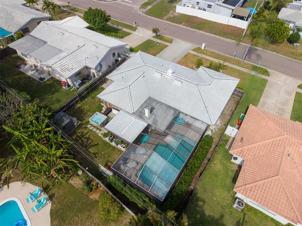 An aerial view shows a house with a white roof, a screened-in pool, and yard — 5676 WILLIAMS BOULEVARD, SEMINOLE, FL