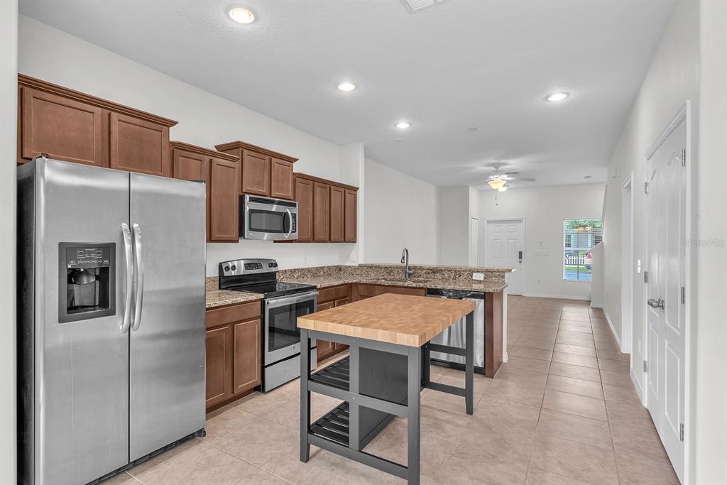 A kitchen with brown cabinets, stainless steel appliances, granite countertops, and a wooden kitchen island — 2719 LANTERN HILL AVENUE, BRANDON, FL