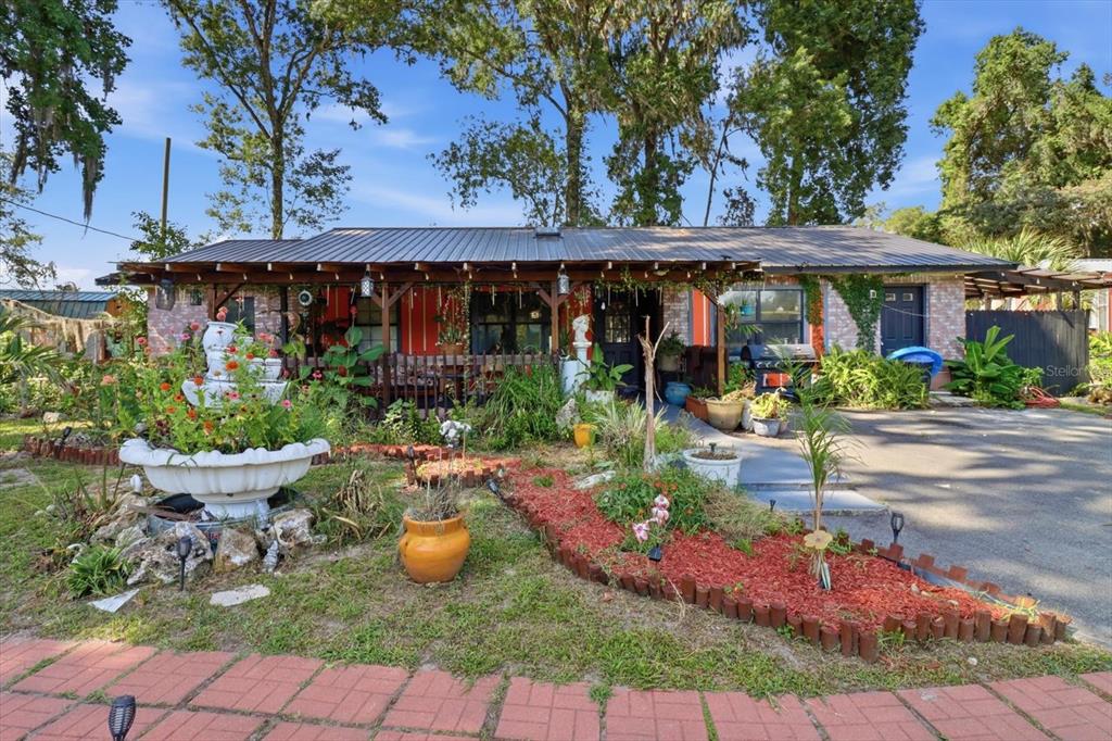 A single-story house with a metal roof, a front porch, and a landscaped front yard — 1736 NW 26TH PLACE, OCALA, FL