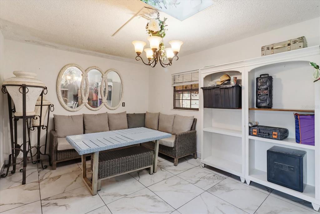 A dining area features a corner wicker sofa, a light-colored table, and white shelving units — 1736 NW 26TH PLACE, OCALA, FL
