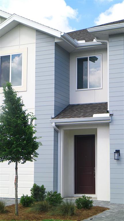 A two-story house exterior features light blue horizontal siding, a dark brown door, and landscaping — 5833 JACKIE MAE PLACE, RIVERVIEW, FL