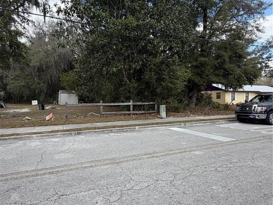 A vacant lot with a wooden fence and a small shed sits beside a street — SE 65TH AVENUE, HAWTHORNE, FL
