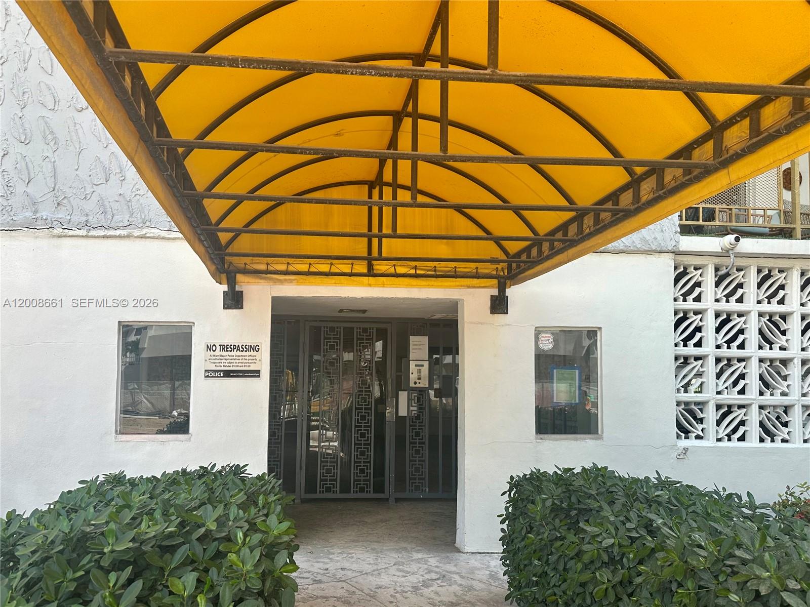 An exterior view of a building entrance featuring a yellow awning and decorative concrete blocks — 1340 Lincoln Rd # 400, Miami Beach FL 33139, MIAMI BEACH, FL