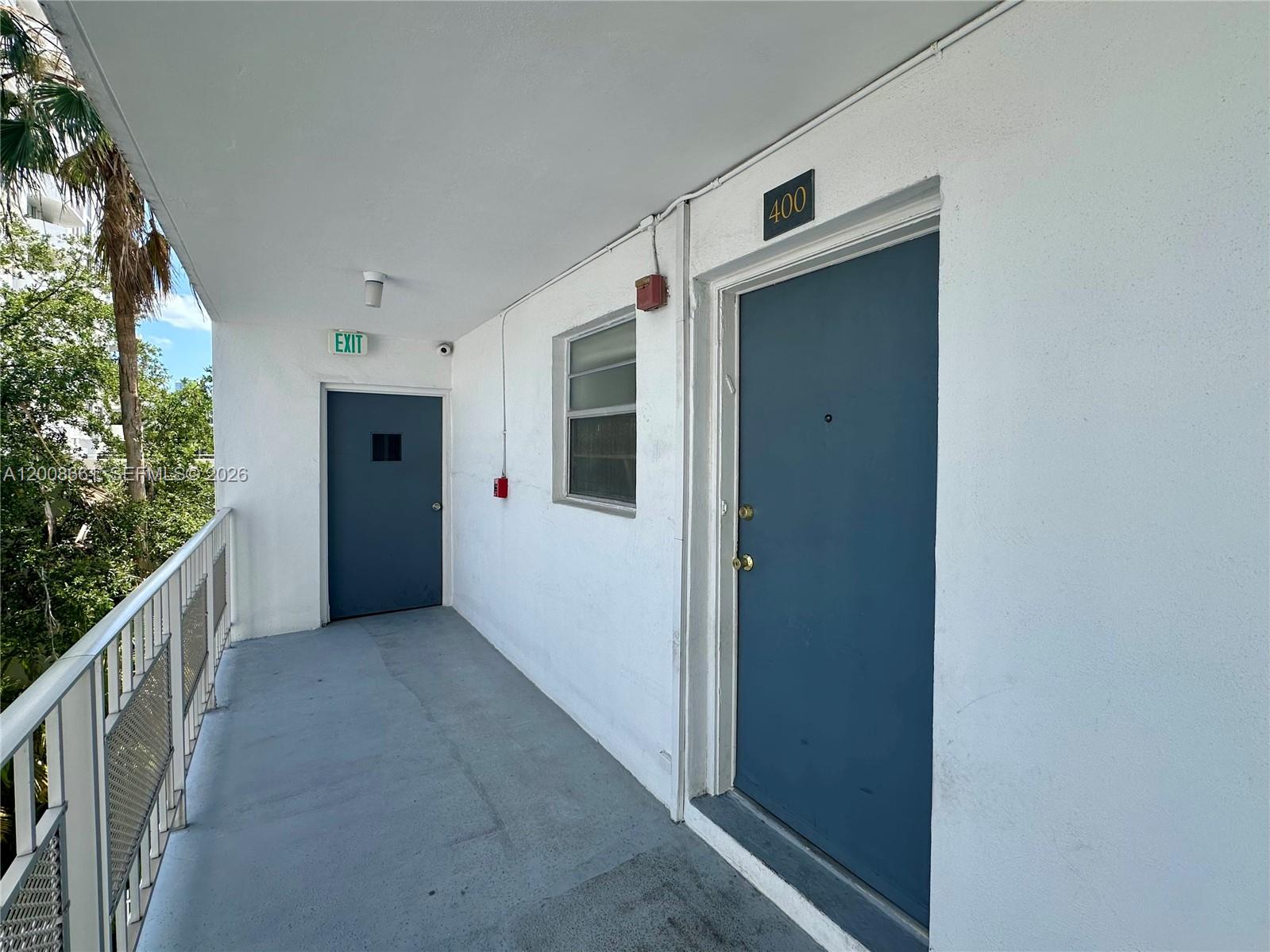 An exterior apartment hallway features a blue door labeled 400, a window, and an exit door — 1340 Lincoln Rd # 400, Miami Beach FL 33139, MIAMI BEACH, FL
