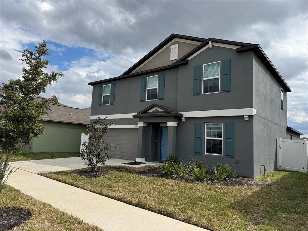 A two-story gray house with a blue front door, attached garage, and white shutters — 13319 GREAT PLAINS DRIVE, RIVERVIEW, FL