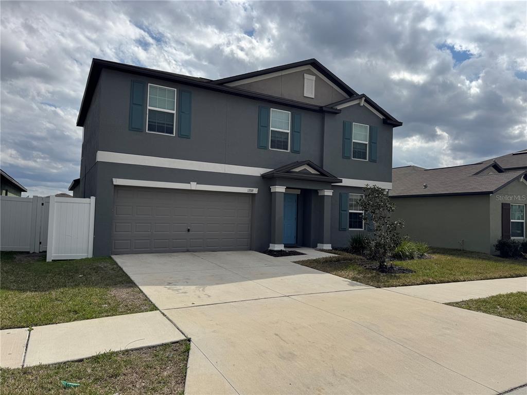 A two-story gray house with a two-car garage and a blue front door — 13319 GREAT PLAINS DRIVE, RIVERVIEW, FL