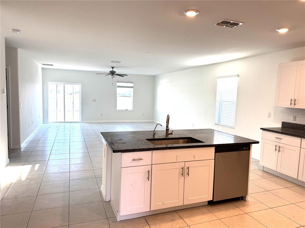 A kitchen island with a sink and dishwasher sits in an open-concept living area — 13319 GREAT PLAINS DRIVE, RIVERVIEW, FL