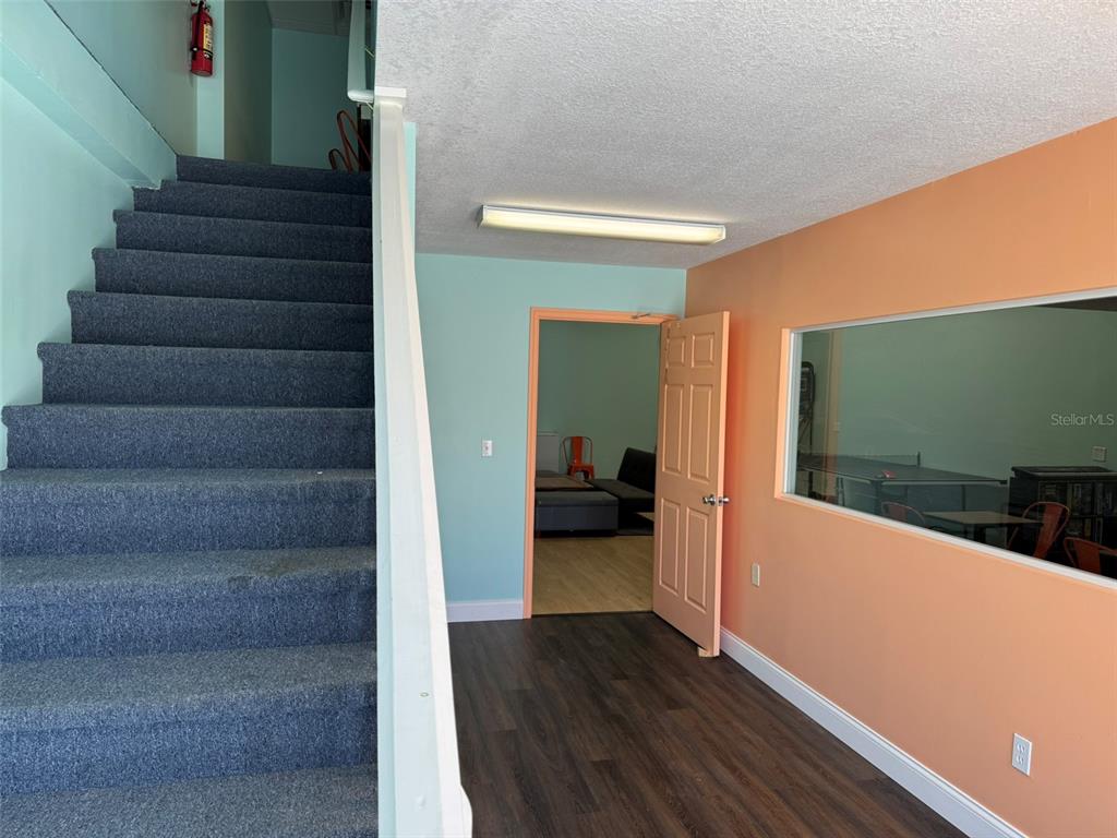 A carpeted staircase leads up beside a room with peach walls and a viewing window — 2323 N STATE STREET UNIT 76, BUNNELL, FL