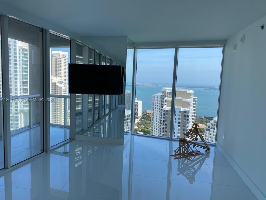 A modern room with white tile floors, floor-to-ceiling windows, and a view of the ocean — 495 Brickell Ave # 2902, Miami FL 33131, MIAMI, FL
