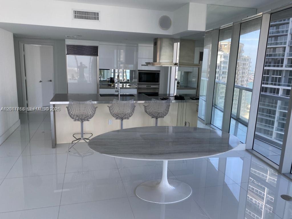 A modern kitchen features a marble-topped island, three wire chairs, and floor-to-ceiling windows — 495 Brickell Ave # 2902, Miami FL 33131, MIAMI, FL