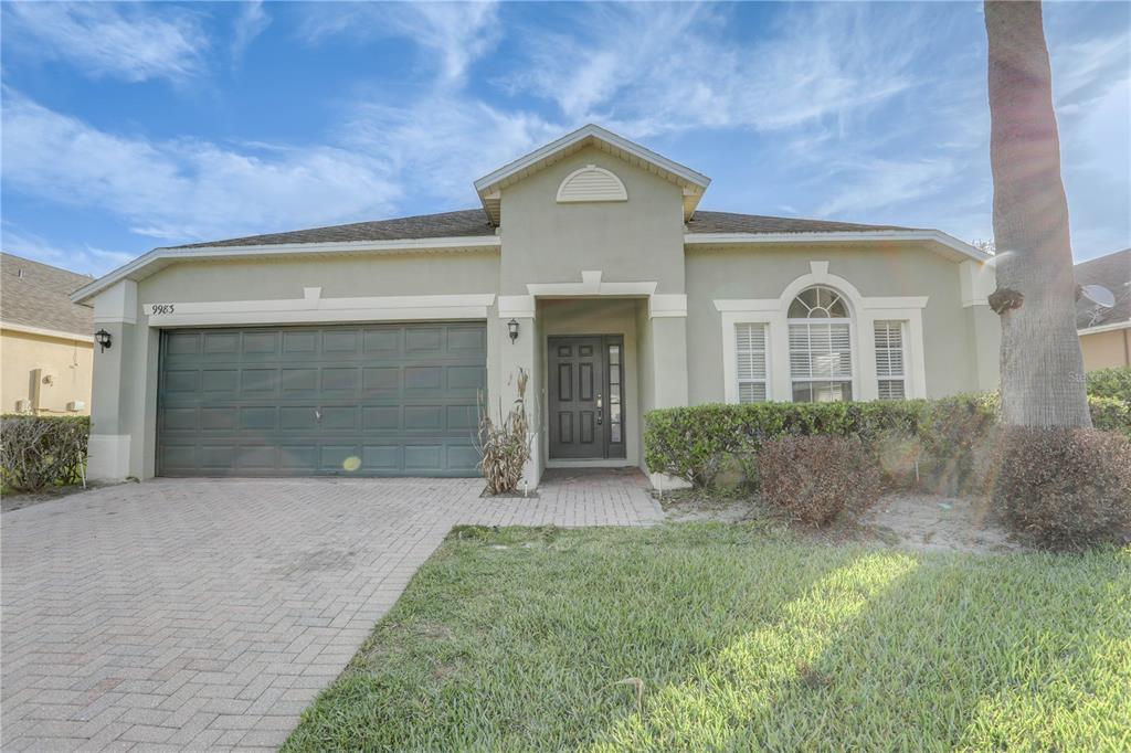 A single-story house with a green stucco exterior, a two-car garage, and a paved driveway — 9983 BRODBECK BOULEVARD, ORLANDO, FL
