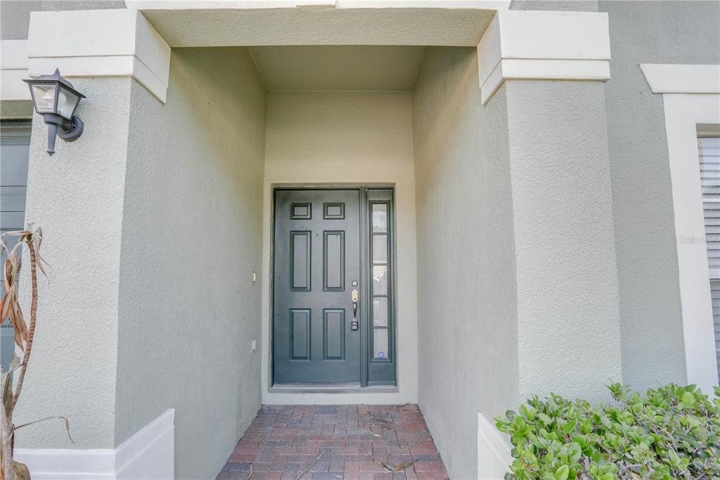 A front entryway with a dark gray door, a side window, and a brick floor — 9983 BRODBECK BOULEVARD, ORLANDO, FL