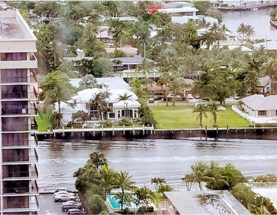 A sandy beach features a large orange umbrella, lounge chairs, and palm trees by the ocean — 2030 S Ocean Dr # 1802, Hallandale Beach FL 33009, HALLANDALE BEACH, FL
