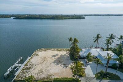 An aerial view shows a vacant waterfront lot next to a house with palm trees — VERO BEACH, FL