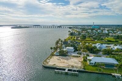 An aerial view of a waterfront vacant lot with a private dock and nearby homes — VERO BEACH, FL
