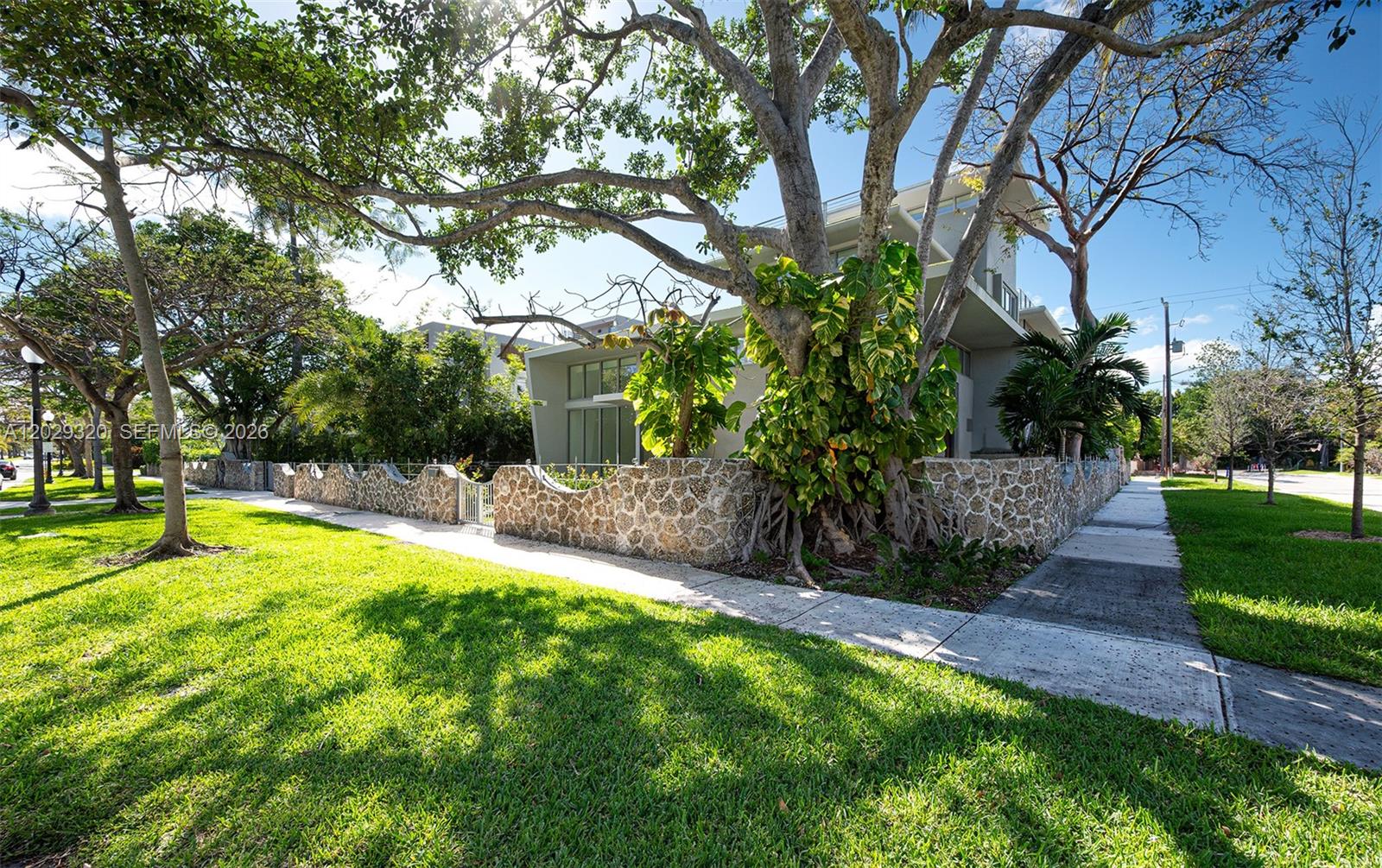 A modern house with a stone wall is partially obscured by a large tree — 2100 S Miami Ave, Miami FL 33129, MIAMI, FL