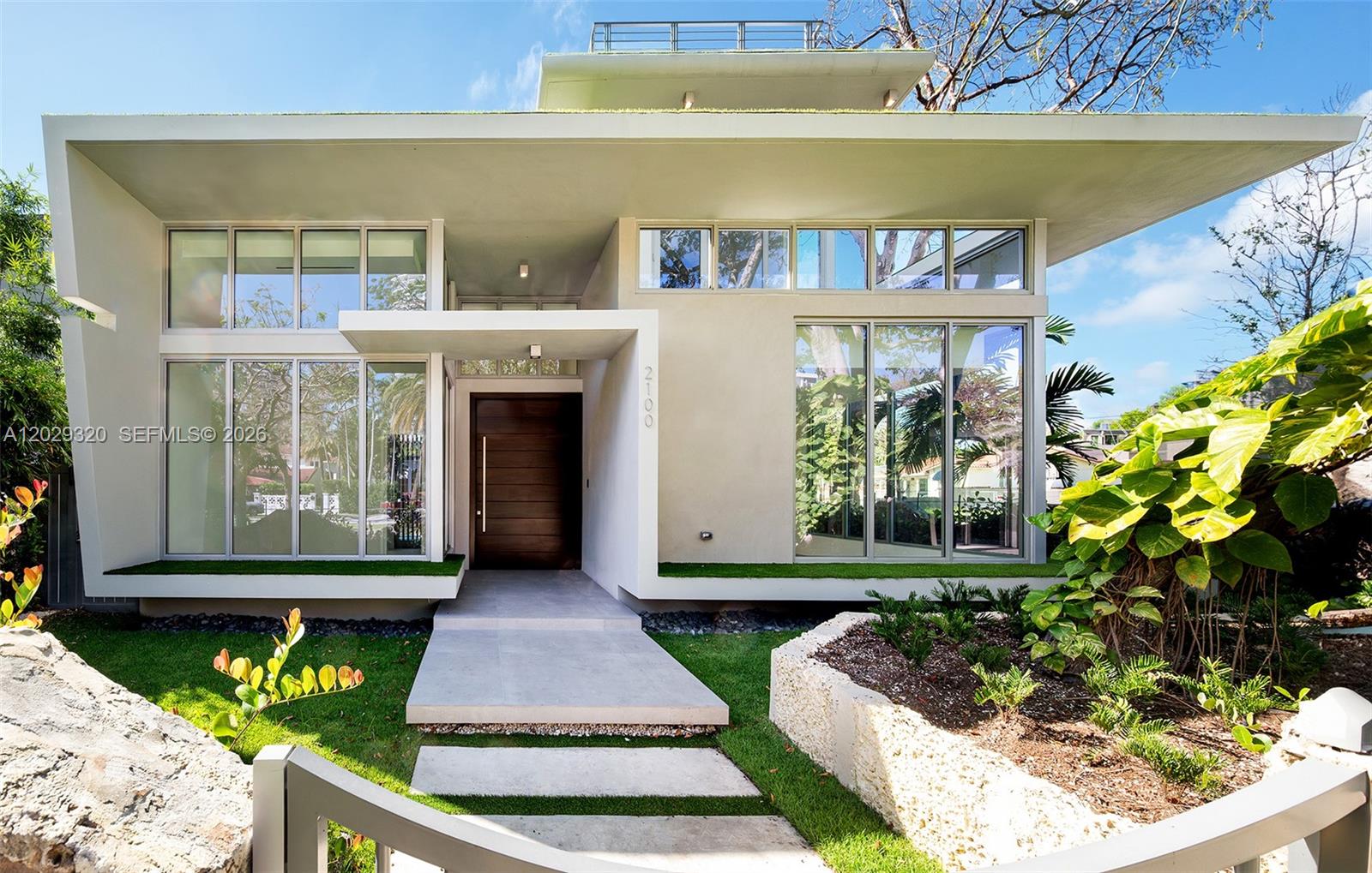 A modern house exterior features large glass windows, a flat roof, and a wooden door — 2100 S Miami Ave, Miami FL 33129, MIAMI, FL