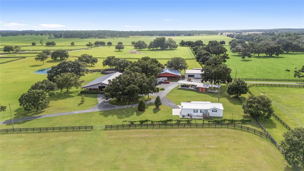An aerial view shows a rural property with a house, barns, and fenced pastures — 18800 SE 47TH PLACE, MORRISTON, FL