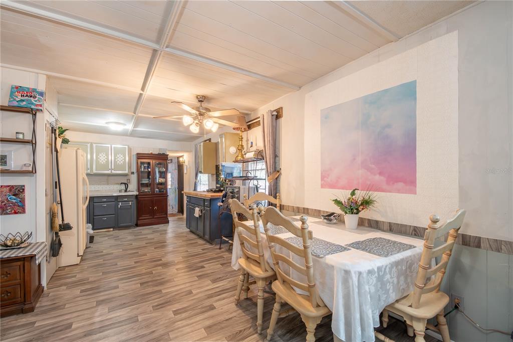 A dining area with a table and chairs leads into a kitchen with dark cabinets — 3355 SE 92ND STREET, OCALA, FL