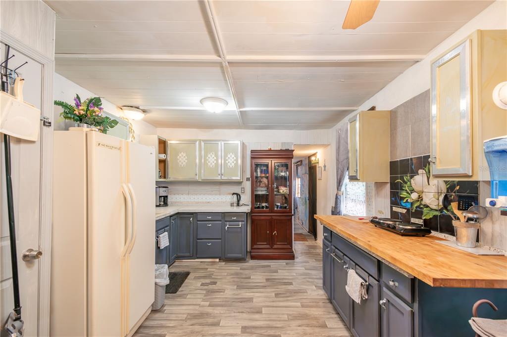 A kitchen features blue lower cabinets, light-colored upper cabinets, a wood countertop, and white appliances — 3355 SE 92ND STREET, OCALA, FL