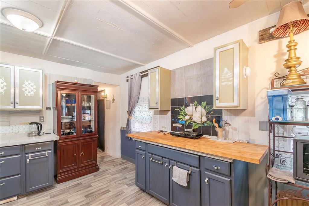 A kitchen features blue cabinets, a wood countertop, a floral tile backsplash, and wood flooring — 3355 SE 92ND STREET, OCALA, FL