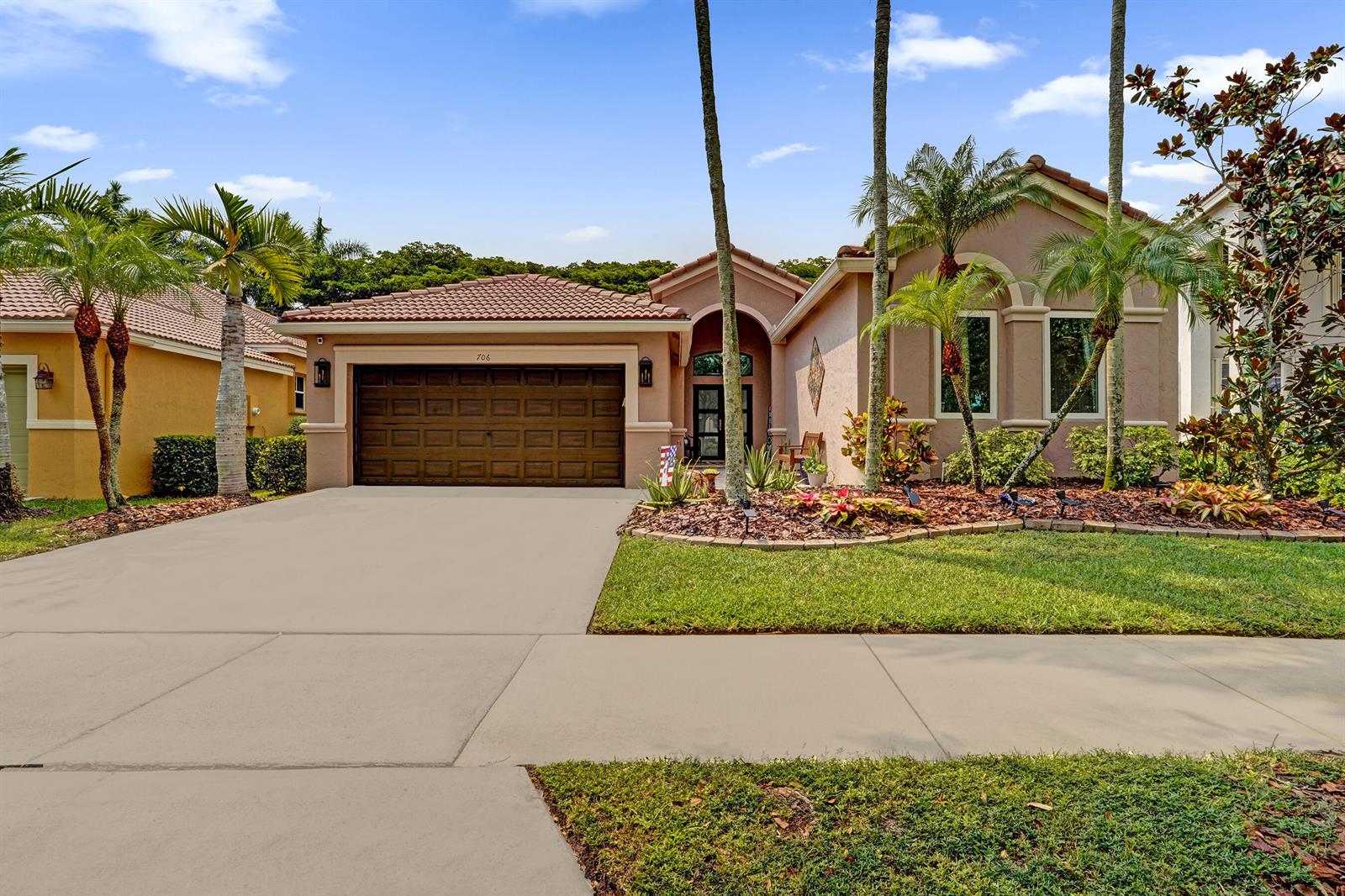 A single-story house with a brown garage door, tile roof, and palm trees in front — 706 Tulip Circle, Weston FL 33327, WESTON, FL