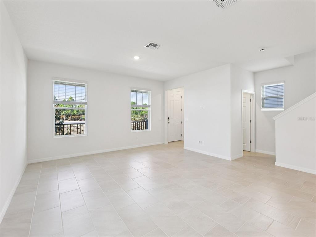 An empty living room with white walls, light tile flooring, and two windows — 4680 HOMESTEAD TRAIL, ST CLOUD, FL